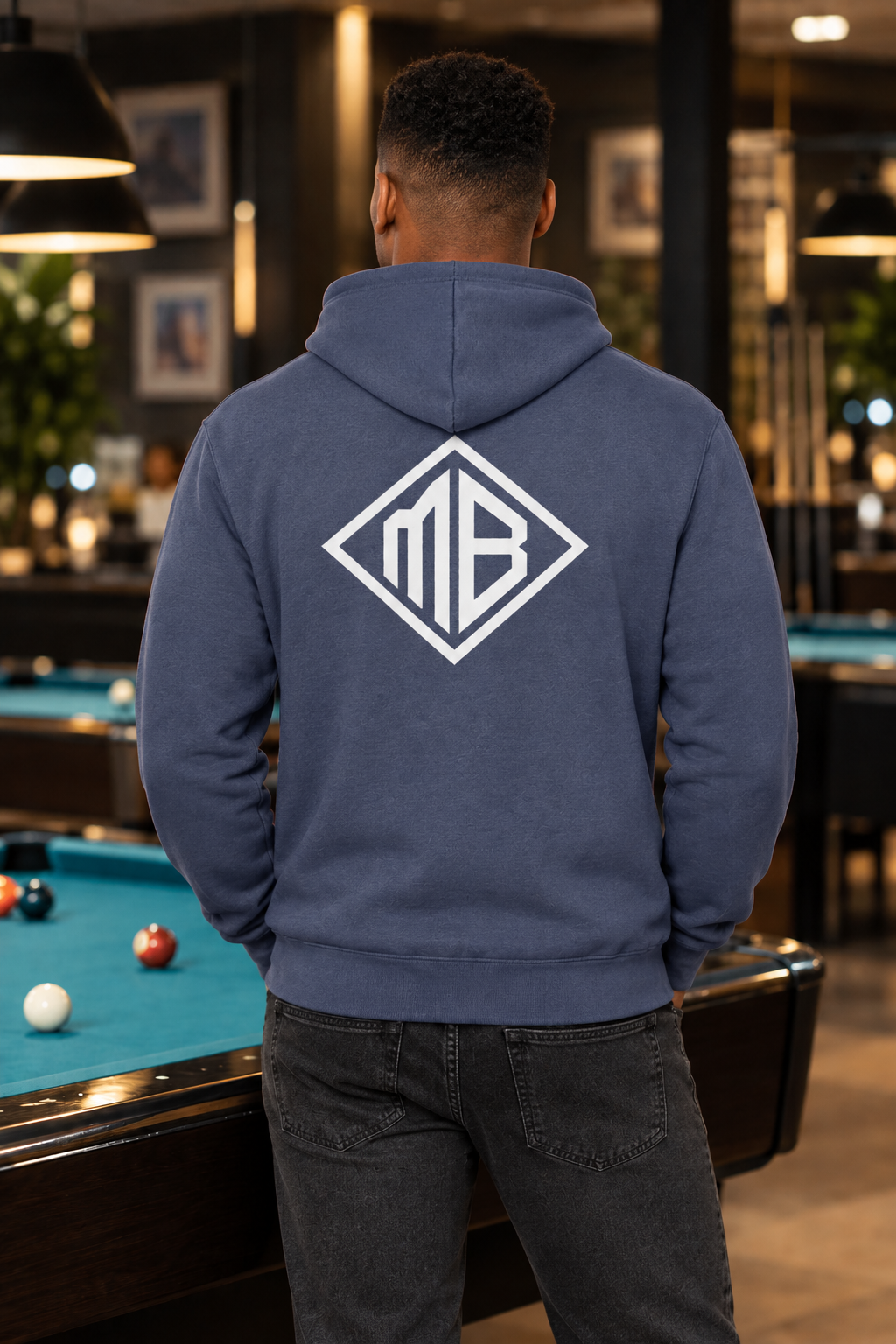 Rear-view model wearing the blue hoodie with white MB diamond
