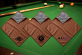 Three brown-and-grey cue cloths with corner logos on a pool table
